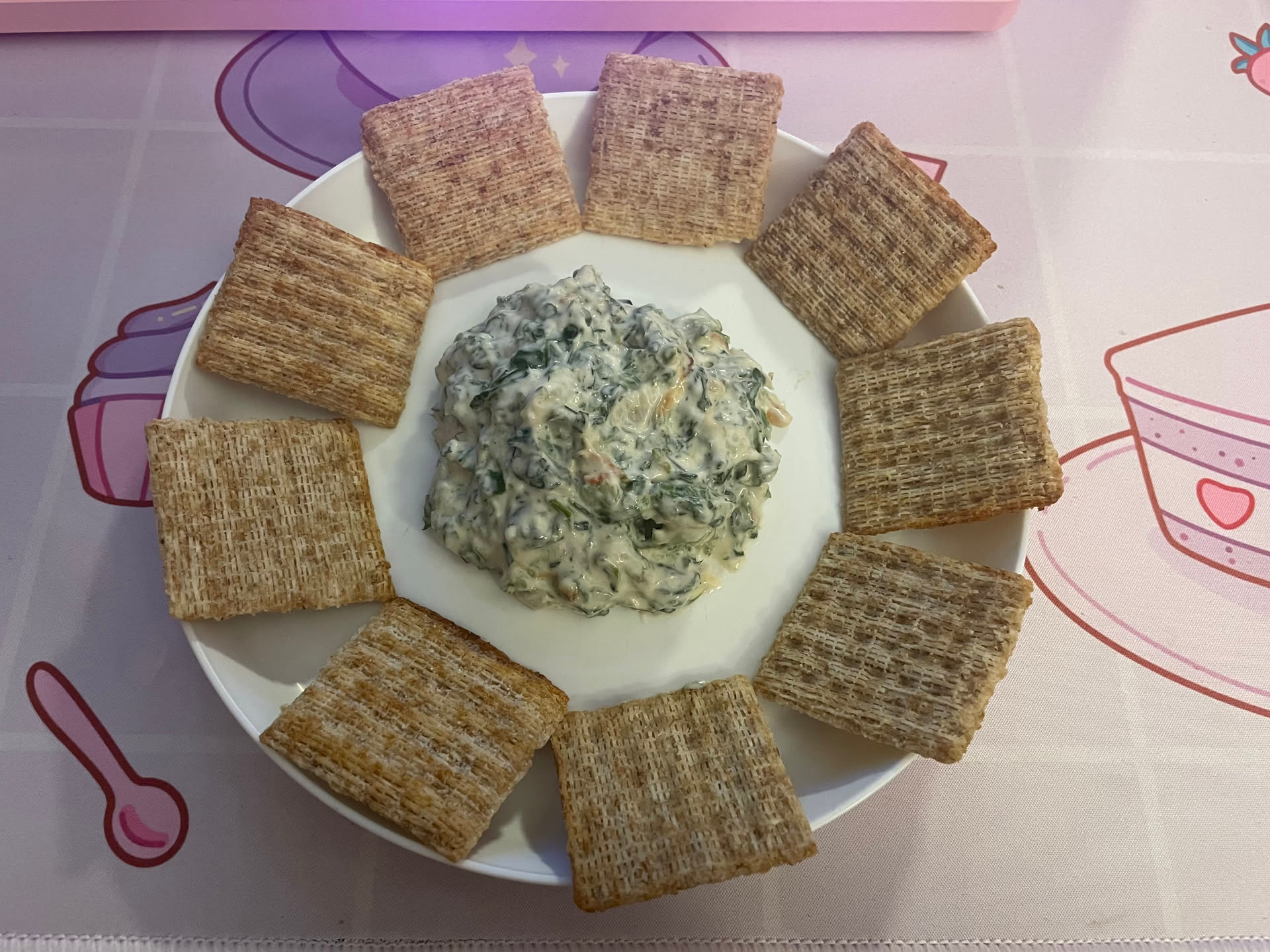 Image of the spinach dip on a plate with some Triscuts
