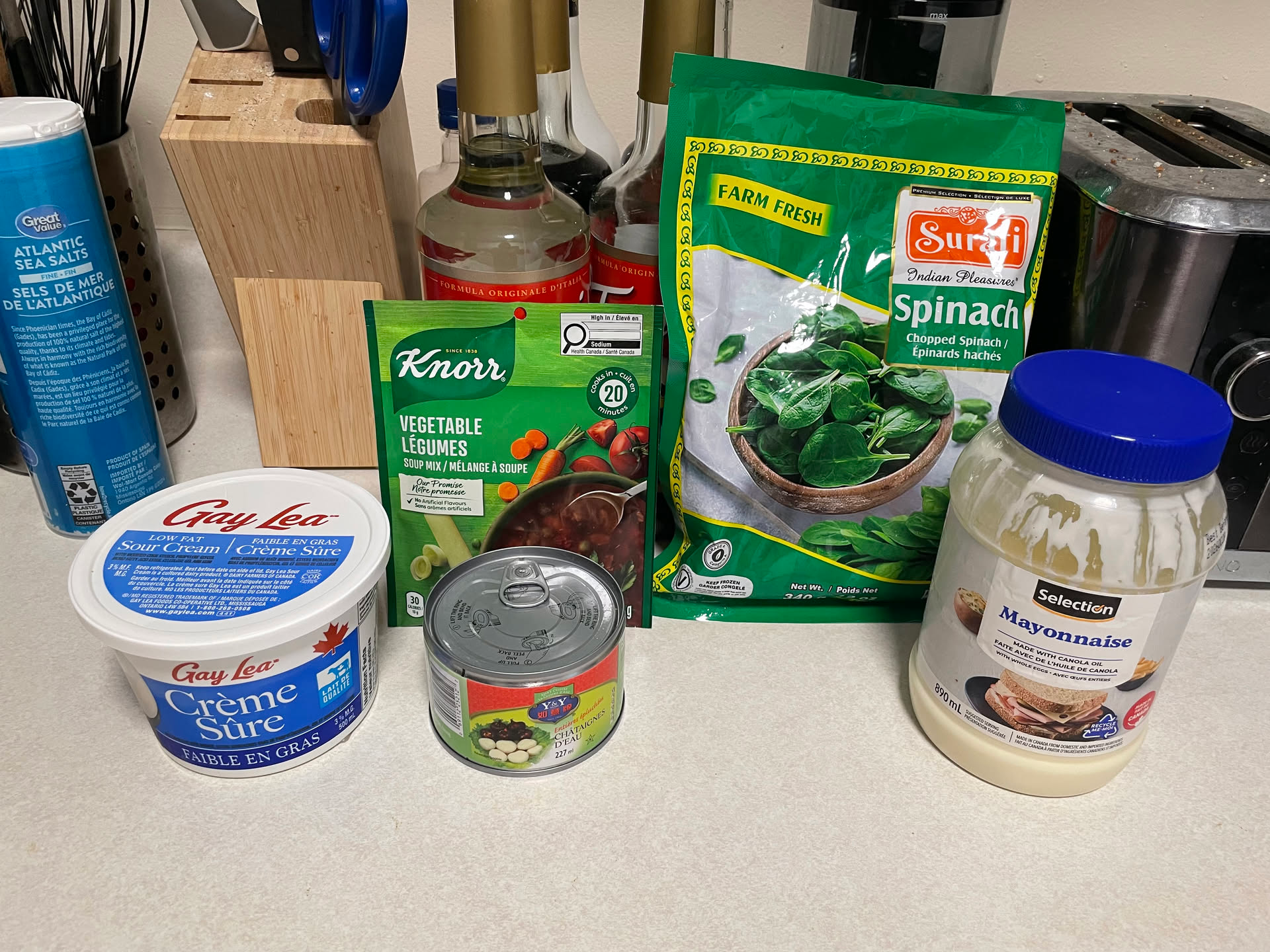 List of ingredients from left to right: sour cream, dry vegetable soup mix, canned water chestnuts, frozen spinach, mayonnaise